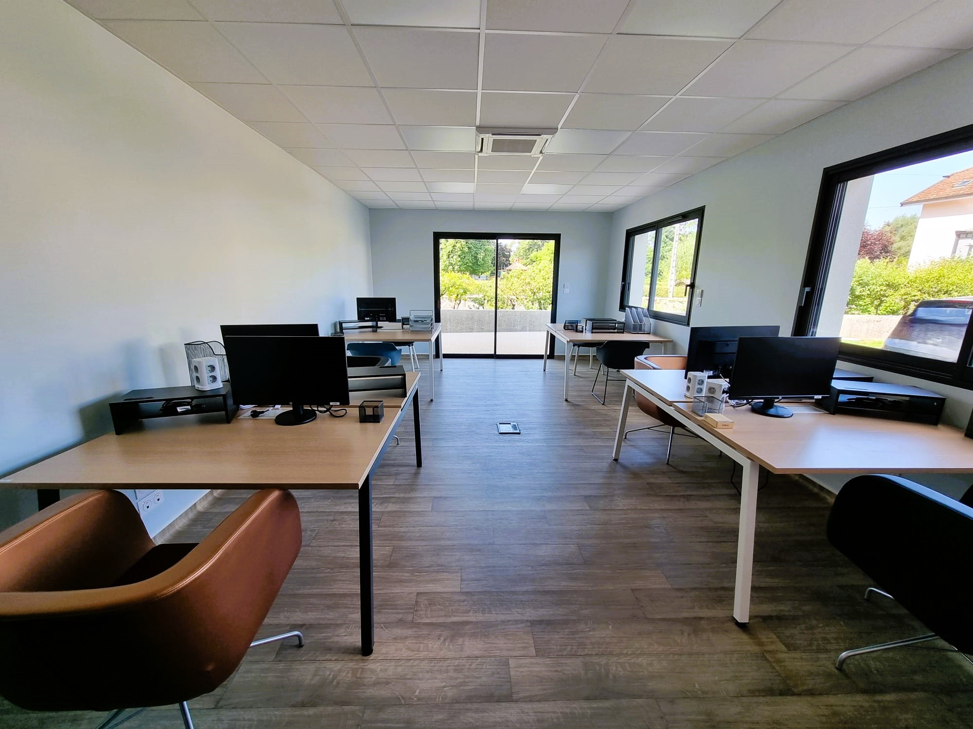 image d'une pièce coworking avec des tables, chaises, écran